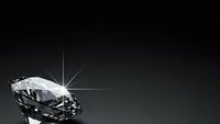 Sparkling diamond with brilliant light rays on dark gradient background for luxury jewelry and precious stone concepts.