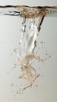 Dynamic water vortex with beige tones creates abstract swirling formation underwater, featuring air bubbles and fluid motion against light background.