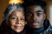 Elderly African American grandmother and young adult grandson sharing intimate family moment together, warm lighting creates emotional generational bond portrait.