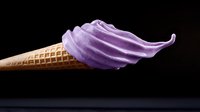 Soft serve purple ice cream swirled in waffle cone against dark background, frozen dessert photography with dramatic lighting and minimalist composition.