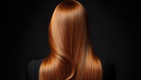 Smooth copper-toned hair flowing in waves against dark background, showing healthy shine and professional styling. For beauty and hair care advertising.