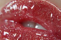 Sensual close-up of glossy red lips with sparkly glitter makeup and shimmering effect, showing glamorous beauty detail in macro photography for cosmetic and fashion industry.