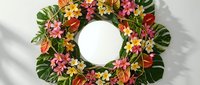 Tropical floral wreath with vibrant plumeria flowers and monstera leaves on white background. Colorful Hawaiian-style decoration for summer events.