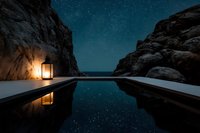 Infinity pool between rocky cliffs under starry night sky with glowing lantern creating peaceful luxury resort atmosphere for relaxation and travel content.