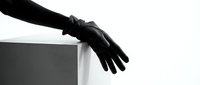 Black leather gloved hand resting on white cube surface against white background, isolated for design use on apparel and graphics.