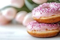 Pink glazed donuts with sprinkles in soft focus macro shot. Fresh baked pastries with sugar pearls decoration on white background for bakery and food design.