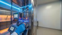 Modern laboratory bioreactor equipment with blue LED lighting and digital control panels for biotechnology research and pharmaceutical manufacturing processes.