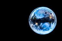 Crystal clear water bubble sphere with air bubbles floating against black background for science education and environmental concepts.