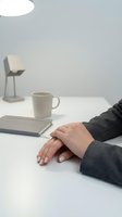 Woman hands resting on white desk in modern minimalist office workspace with coffee mug and notebook for business and productivity concepts.