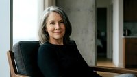 Confident mature Caucasian businesswoman with gray hair smiling in modern office setting, professional corporate portrait for business marketing materials.