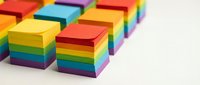 Colorful stacked sticky notes arranged in rainbow order on white background, office supplies for organization and planning.