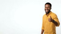 Young man with dark skin tone wearing a bright yellow button-up shirt, smiling and giving thumbs up gesture against white background, suitable for business, lifestyle and motivational content.