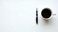 Minimalist workspace with black coffee cup and pen on clean white background for business and productivity concepts.