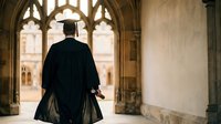 Graduate in black cap and gown standing in Gothic university archway during graduation ceremony, academic achievement and education milestone concept.