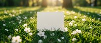 Blank white card mockup on lush green grass with white spring flowers and warm sunlight, perfect for greeting or invitation design.