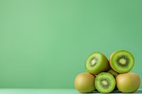 Fresh ripe kiwi fruits arranged on mint green background, whole and halved showing juicy flesh texture, minimalist food composition with copy space.