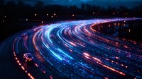 Curved highway at night with long exposure light trails from vehicles creating vibrant blue and red streaks against dark background, capturing motion and speed.