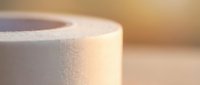 White medical tape roll on wooden surface with warm lighting for healthcare and first aid applications.