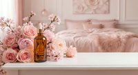 Amber glass serum dropper bottle surrounded by pink roses and peonies on white table in soft blush bedroom setting for beauty branding.