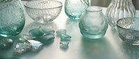 Assorted transparent and frosted glassware in mint and clear tones arranged on neutral surface for home decor, interior design, and product styling projects.
