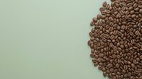 Roasted coffee beans arranged on soft sage green background with copy space for beverage branding, cafe design, or packaging projects.