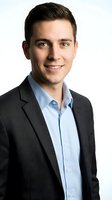 Professional young Caucasian businessman in dark suit and light blue shirt smiling confidently on white background isolated for corporate design.