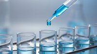 Laboratory pipette dropping blue liquid into test tubes for scientific research and chemical analysis experiments in modern lab setting.