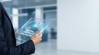 Businessman holding transparent tablet displaying digital security lock icon in modern office environment for cybersecurity and data protection concepts.