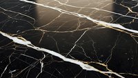 Elegant black marble surface with golden veins and white streaks creating luxurious natural stone texture for interior design and architectural projects.
