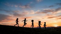 Silhouettes of five children running together across a hillside during golden sunset, depicting joy, freedom, and active outdoor play for lifestyle and wellness campaigns.