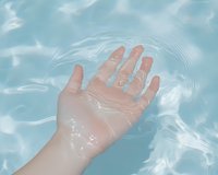 Wet hand gently touching clear blue pool water surface, creating soft ripples. Fresh summer concept for spa, wellness, and nature themes.