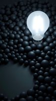 Illuminated light bulb standing upright among scattered dark spheres, symbolizing innovation, creativity, and unique ideas emerging from the crowd for business concepts.