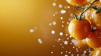 Fresh cherry tomatoes on vine with water droplets against warm golden background for culinary and healthy eating concepts.