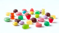 Colorful assorted gummy candies and sweets scattered on white background. Variety of fruit flavored jellies, bears and striped treats for confectionery designs.