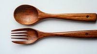 Handcrafted wooden spoon and fork set made from natural oak wood with rich brown grain texture, isolated on white background for kitchen and dining decor.