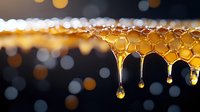 Fresh honey drips from honeycomb structure creating golden drops against dark background with bokeh lights, macro photography showing natural organic texture and flow.