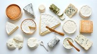 Assorted gourmet cheese collection with soft and hard varieties arranged on white background for culinary and food photography projects.