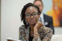 Professional African American businesswoman with glasses and braided hair in modern office setting for corporate presentations and workplace diversity campaigns.