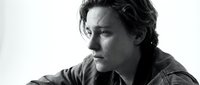 Young Caucasian man with wavy hair in contemplative pose, black and white portrait photography for editorial and commercial use.
