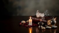 Mystical altar setup with burning candle, crystals, ancient books and ritual objects creating atmospheric spiritual scene for meditation practices.