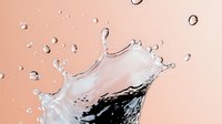 Clear liquid splash crown formation with dark contrast against soft pink background, frozen motion photography capturing dynamic fluid movement and droplets.