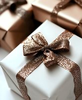 Elegant white gift box with sparkling copper ribbon bow, surrounded by bronze wrapped presents for holiday or celebration.