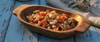 Wooden bowl filled with mixed nuts, dried fruits and healthy snacks on rustic blue table. Nutritious trail mix for organic lifestyle and wellness.