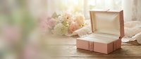 Open wooden jewelry box on rustic table with soft floral background and warm natural lighting creating romantic atmosphere for gift presentation.