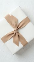 Elegant white gift box tied with a beige fabric ribbon bow on a textured white background, minimal luxury style for holidays.