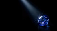 Blue diamond gemstone with brilliant light beam on dark background creating luxury jewelry display with sparkling reflections and dramatic lighting effects.
