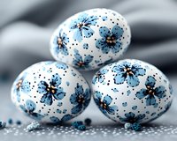 White Easter eggs decorated with delicate blue floral pattern and black dots create elegant holiday composition against soft gray background.
