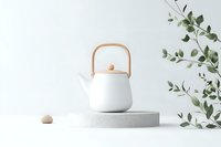 Minimalist white ceramic teapot with wooden handle on concrete podium, decorated with eucalyptus branches against light background. Modern zen composition.