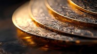 Macro shot of stacked antique silver coins with ornate engraved patterns catching warm golden light against dark background, showing fine detail and texture.