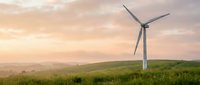 Wind turbine standing in green rolling hills at sunset, generating renewable energy for sustainable power production and clean technology.